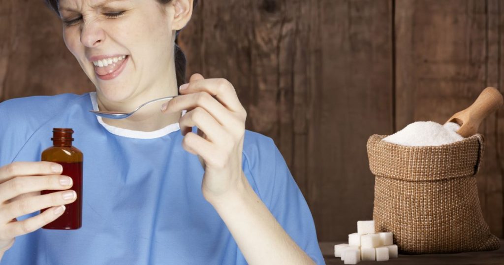 A woman in a blue shirt makes a sour face while holding a spoonful of medicine, with a sack of sugar and sugar cubes nearby—suggesting the idea of "a spoonful of sugar helps the medicine go down.