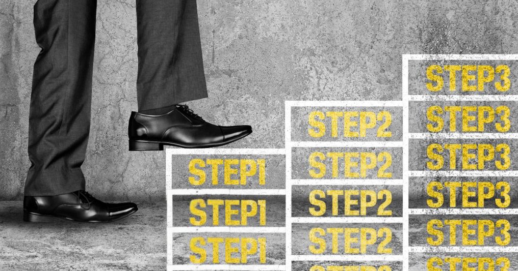 A person in dress shoes and slacks climbs steps labeled Step 1, Step 2, and Step 3—symbolizing a clear, structured approach to progress or achieving goals.